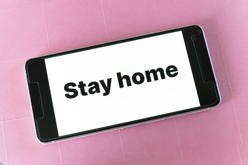 Mobiltelefon med teksten "Stay home" (Bli hjemme)