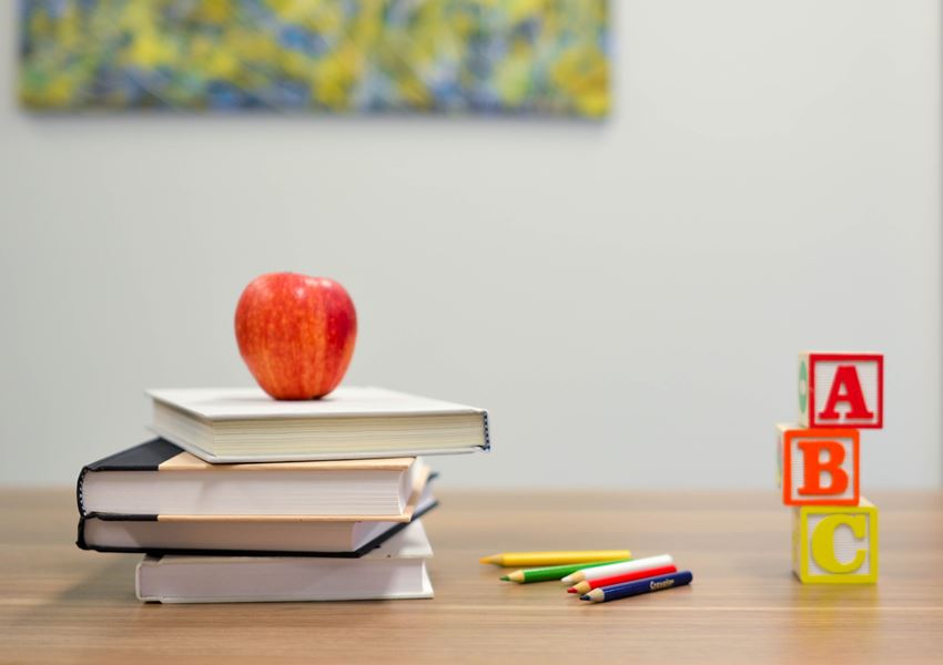 Skolebøker med et rødt eple på toppen