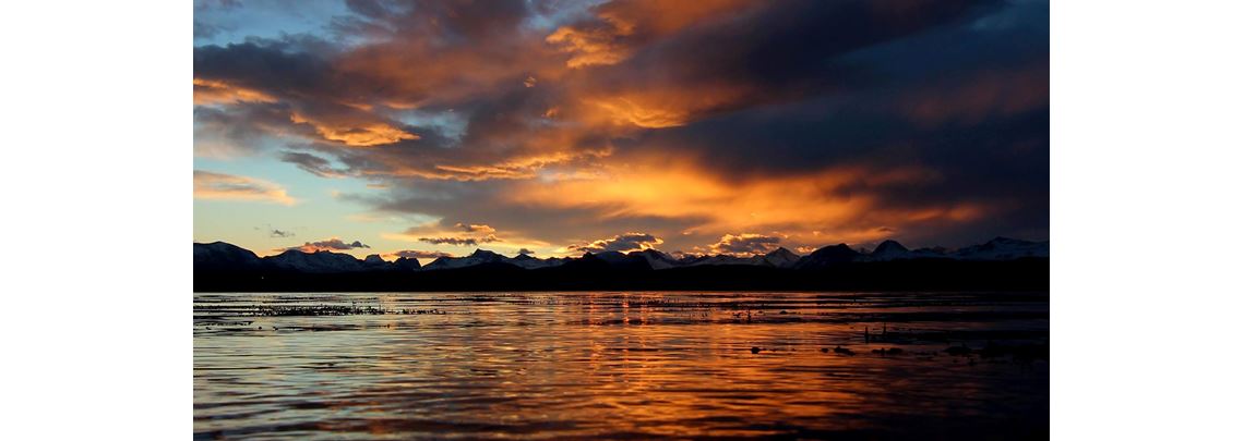 Illustrasjonsfoto av et hav i solnedgang, med fjell i bakgrunnen